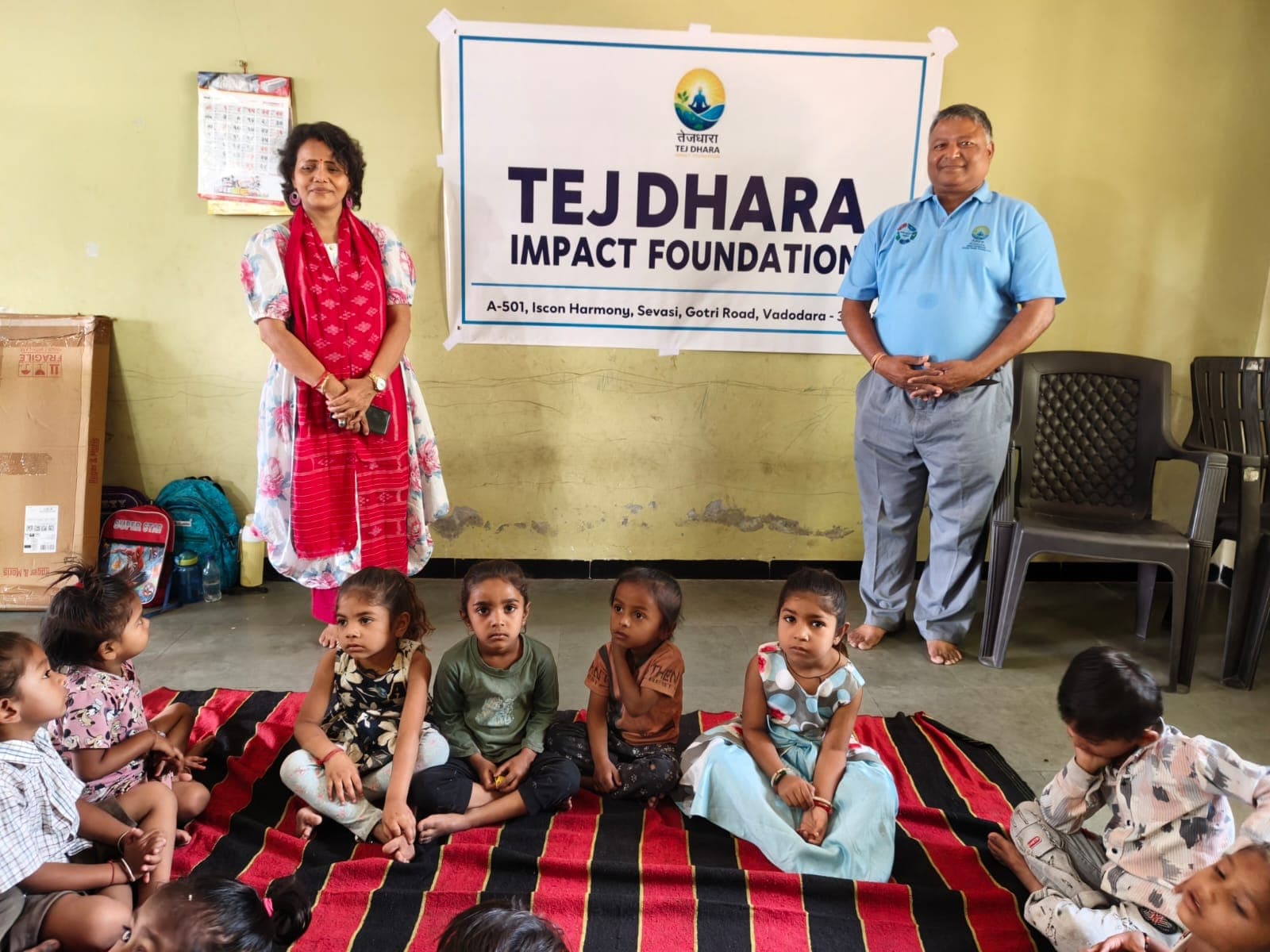 Group photograph of the children with Tej Dhara founders in front of the banner